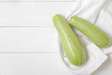 Fresh green zucchini on white wooden background