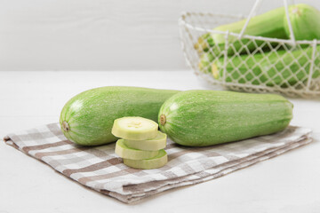 Fresh green zucchini on white wooden background