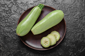 Plate with fresh green zucchini on black background