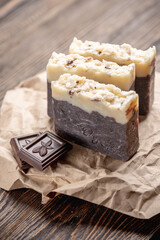 Pieces of natural handmade chocolate soap on a kraft paper wrapper on a wooden table