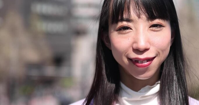 A 2x slow motion of Japanese woman portrait behind cherry blossom closeup handheld