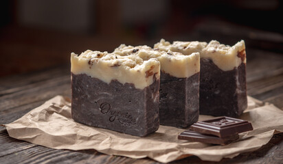 Pieces of natural handmade chocolate soap on a kraft paper wrapper on a wooden table