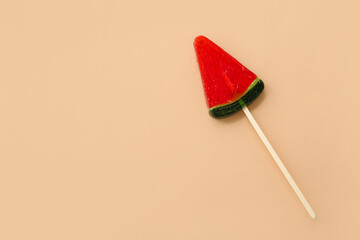 Lollipop in shape of watermelon slice on beige background