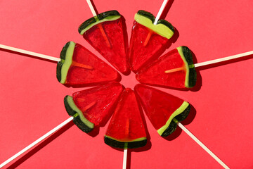 Lollipops in shape of watermelon slice on red background