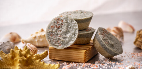 Natural soap with sea salt on a wooden soap dish, shells and a starfish. Organic summer soap, immersing in the marine atmosphere