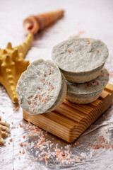 Natural soap with sea salt on a wooden soap dish, shells and a starfish. Organic summer soap, immersing in the marine atmosphere
