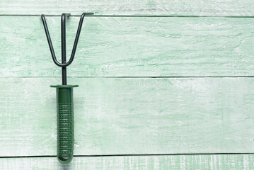 Gardening rake on green wooden background