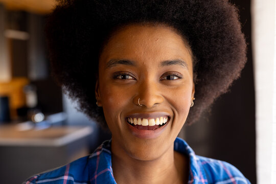 Portrait of happy african american woman with afro and nose ring smiling in kitchen
