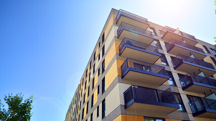 A modern residential building in the vicinity of trees. Ecology and green living in city, urban environment concept. Modern apartment building and green trees. Ecological housing architecture. 