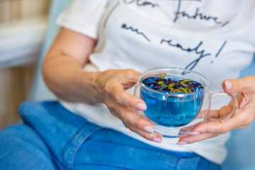 A glass cup with herbal tea in woman's hand