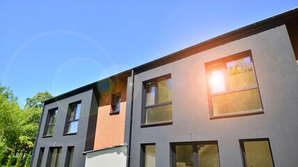 New single family houses in a new development area. Residential homes with modern facade. Terraced family homes in newly developed housing estate. The real estate market in the suburbs.