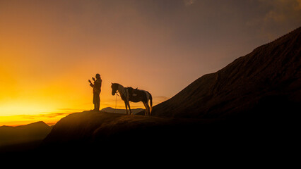 a Muslim praying and being followed by his horse at sunset
