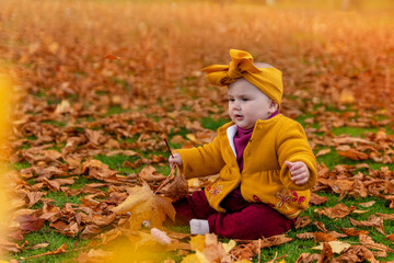 a child in a cap, a yellow blouse and burgundy pants in an autumn park