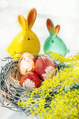 Easter eggs in a nest with a bouquet of mimosa. Arrangement With Easter Eggs And Mimosa. Spring floral concept