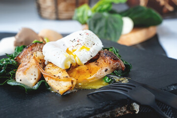 Grilled Pleurotus eryngii mushrooms with poached egg and spinach. Hot fried mushrooms on a spinach substrate is a dietary low-calorie food
