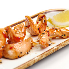 Chicken yakitori with soy glaze and sesame seeds on white. For the restaurant menu.