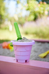 pink bucket and green scoop in the sandbox.