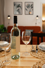 A bottle of wine and glasses on the table. Setting the table in the living room