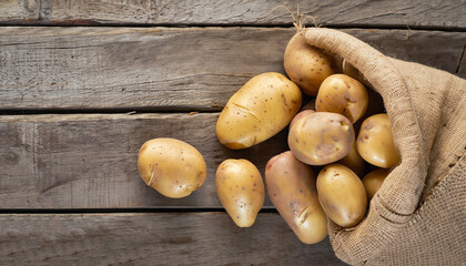 Raw potato food . Fresh potatoes in an old sack on wooden background. Free place for text. Top view - Powered by Adobe
