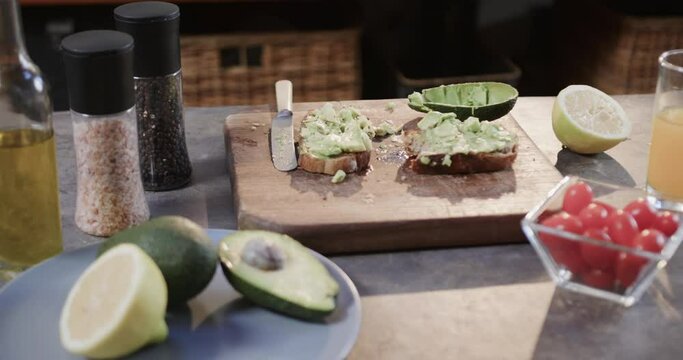 Close up of avocado toast, vegetables and juice in kitchen, slow motion