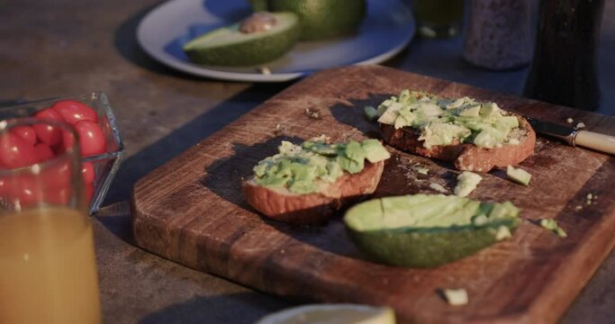 Close up of avocado toast, vegetables and juice in kitchen, slow motion
