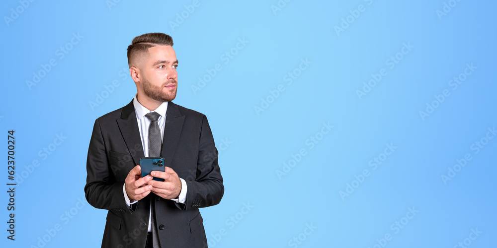 Wall mural serious bearded young european businessman with smartphone looking to the right