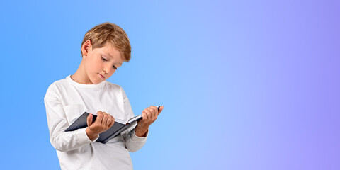 Smart school boy with book in hands reading on copy space background