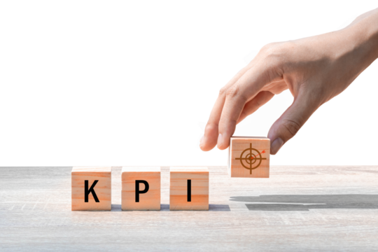 Wooden cube with KPI text on wooden table, blue background. Business ideas to goals.PNG