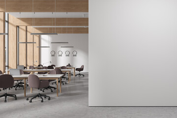 White and wooden coworking office interior with clocks and blank wall