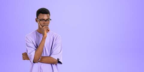 Thoughtful black man student looking down on copy space purple background