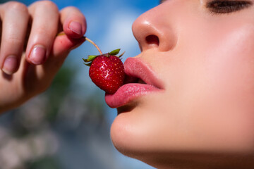 Strawberry in lips. Red strawberry in woman mouths close up.