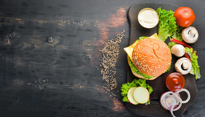 The Burger and the fresh ingredients on the old Board. On a black chalkboard. Top view.