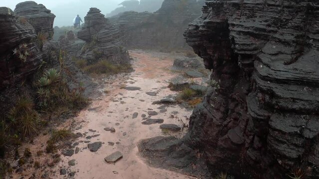 POV hiking on flat topped of Mount Roraima with rock eroded formations in rainy day, Canaima National Park, Venezuela, South America