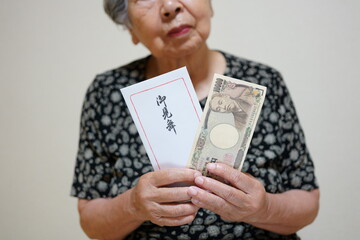 お見舞い袋とお金を持つ高齢女性　顔無し