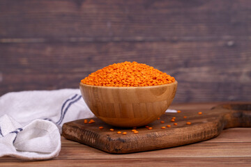 Red lentils on wood background. Raw red lentils in wooden bowl