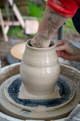Making of mud pot on potters wheel during workshop outdoor
