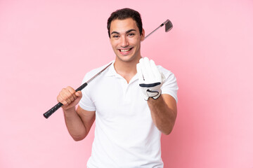 Young golfer player man isolated on pink background inviting to come with hand. Happy that you came