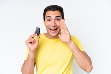Young caucasian man holding car keys isolated on white background shouting with mouth wide open