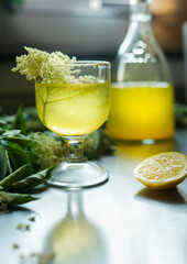 Glass of delicious elderflower lemon liqueur with fresh elderflowers. Front view