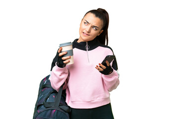 Young sport woman with sport bag over isolated chroma key background holding coffee to take away and a mobile while thinking something