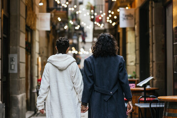 Obraz premium Couple of men walking away down an alley in the city holding hands.