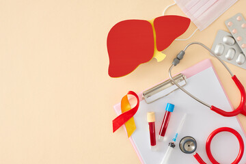 Fototapeta na wymiar Hepatitis prevention concept. Top view photo of liver, clipboard, awareness ribbon, drugs, medical mask, stethoscope, blood tubes, syringe on pastel beige background with empty space for text