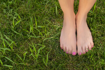 female feet stand barefoot on the green grass