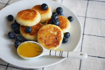 Homemade cheese dessert with honey and blueberries on a checkered linen tablecloth