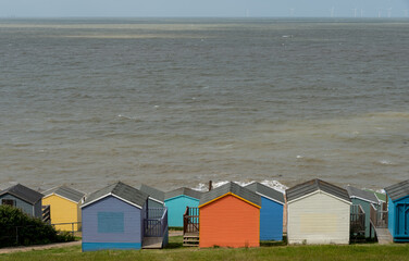 Colourful holiday wooden beach huts facing the calm ocean.