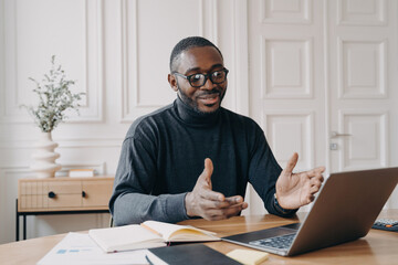 Smiling African American businessman on laptop call, enjoying video conference with colleague.