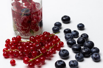 Sprigs of red currant and blueberries on the table. Summer berry drink in a bottle.