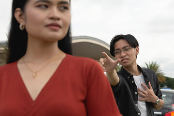 A desperate young man begs for his girlfriend not to abandon him, reaching out with his arms. A tired woman gives up walks away from her clingy boyfriend.