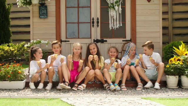 A group of small children of different races eat ice cream and enjoy a warm summer day on the terrace. Advertising happy children and healthy food.