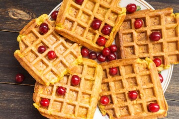 Dish with delicious Belgian waffles on a wooden background, close-up.